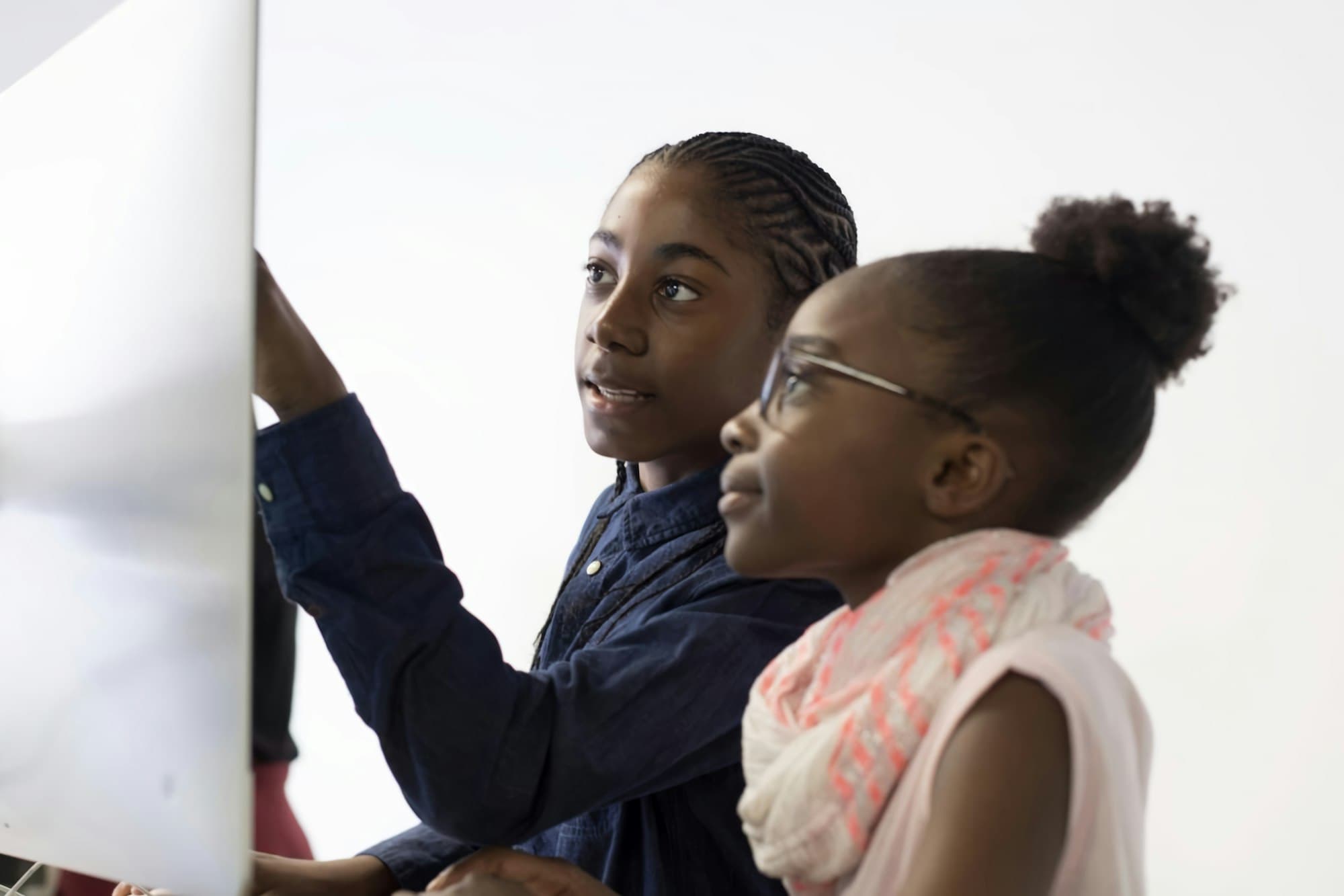 Two schoolgirls working through a lesson together in a bright classroom